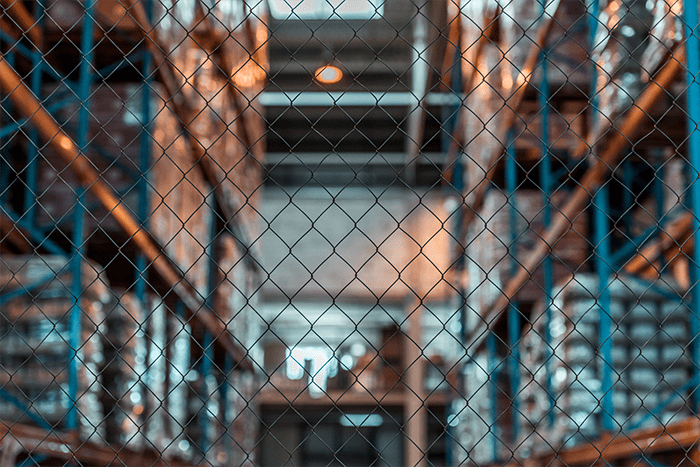 A close up of metallic mesh in front of a warehouse background with racking.