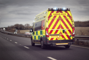 A British Ambulance rushing down the motorway with its blue lights on.