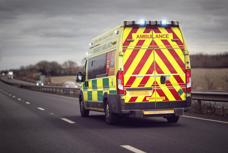 A British Ambulance rushing down the motorway with its blue lights on.