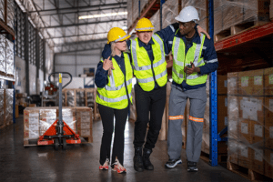 Injured warehouse worker is supported by two colleagues as he attempts to walk