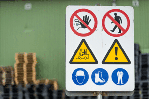 A photo showing safety signs at the entrance of a warehouse, including yellow forklift signs and blue uniform requirements signs.