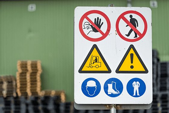 A photo showing safety signs at the entrance of a warehouse, including yellow forklift signs and blue uniform requirements signs.