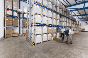 ALT TEXT: A photo of a management team assessing a warehouse’s organisation by looking at a racking system.