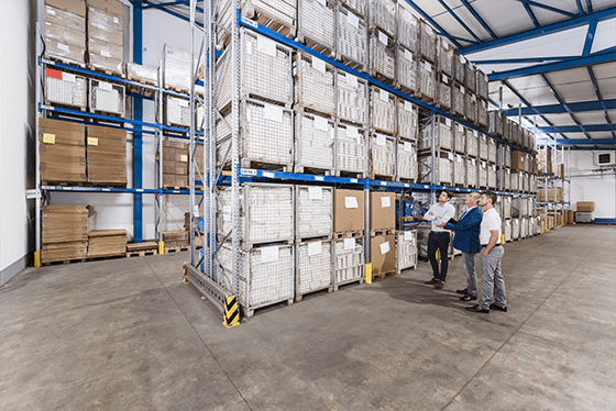 ALT TEXT: A photo of a management team assessing a warehouse’s organisation by looking at a racking system.