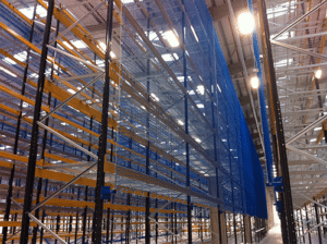 A photo of high-bay racking equipped with back-of-rack netting inside a well-lit warehouse.