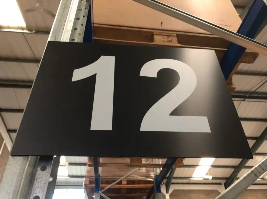 Photo of of aisle markers provided by ELAN for 3PL, using their branded colours of white font on a black background.