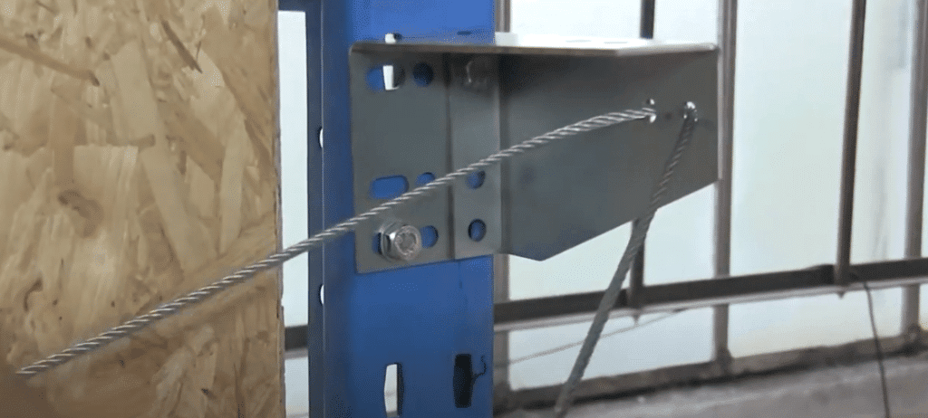 Man attaching cable to a main bracket by passing the wire through the holes.