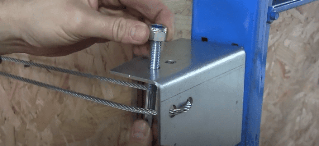 Man passing the stud-end from below into one of the holes of the bracket.