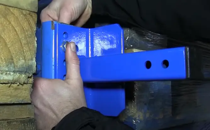 Close-up showing someone fitting the main bracket of a back-of-rack netting system.