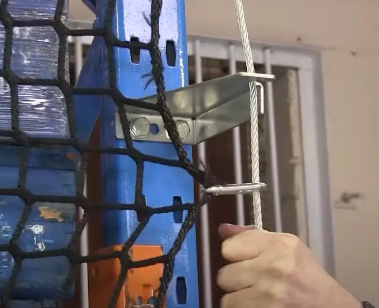 Close up shot of someone hooking the side cable of a back-of-rack netting system to a side bracket