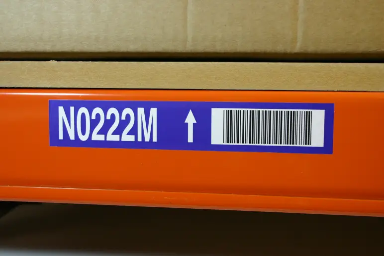 Photo showing a blue barcoded location label on an orange racking beam.